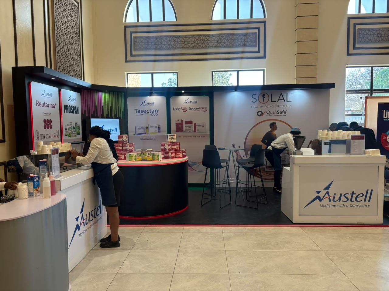 Custom exhibition stand built for Austell, with a curved product display counter and co-branded SOLAL messaging