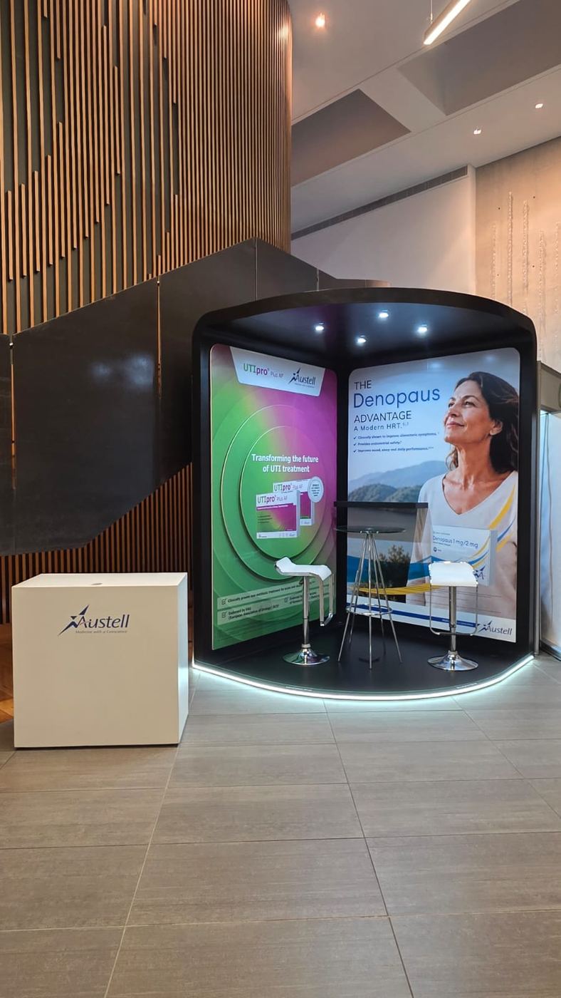 Custom exhibition stand built for Austell, with curved feature walls and branded backlit panels