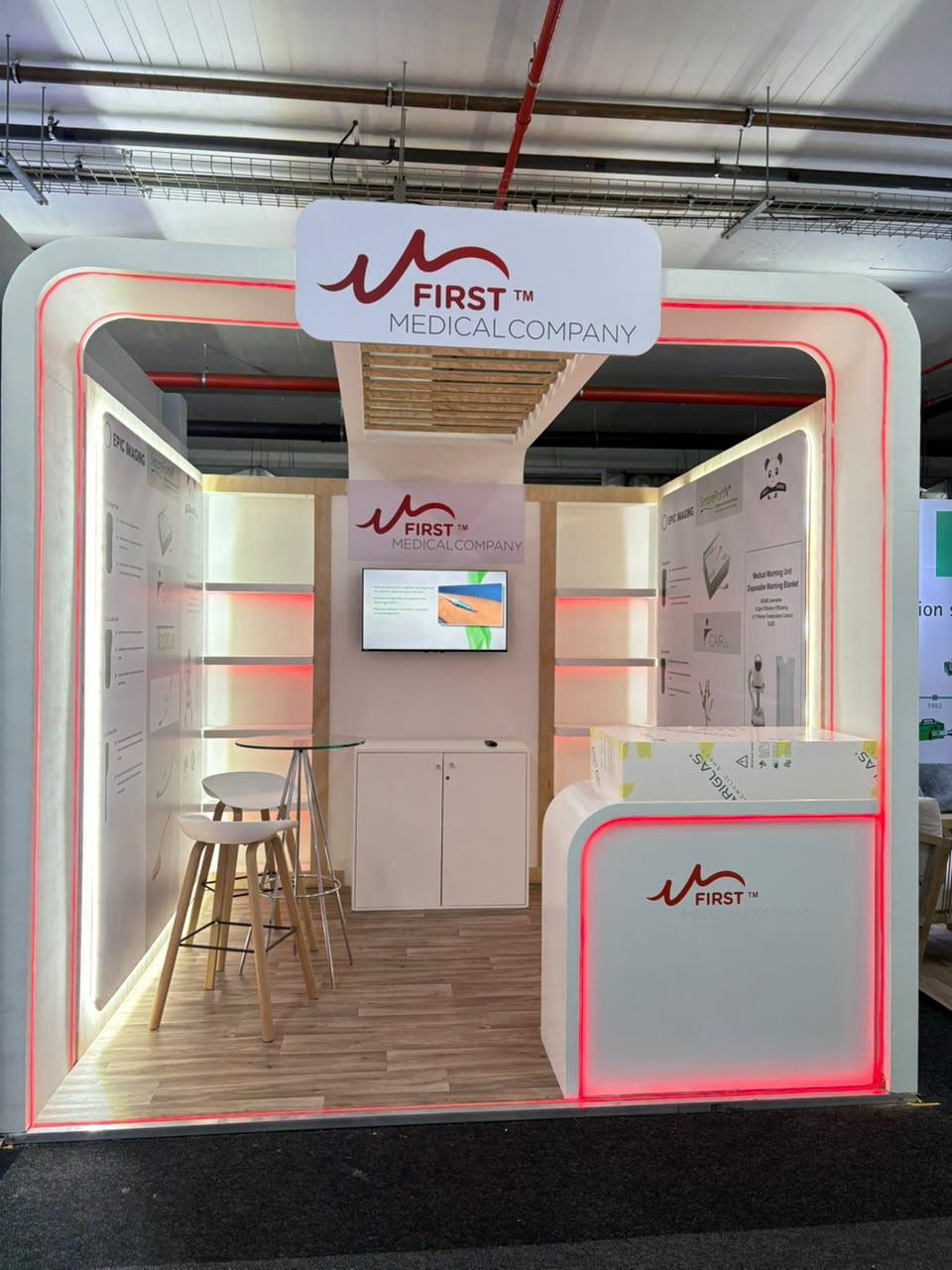 Custom exhibition stand built for First Medical Company, with illuminated red trim, product information panels and bar seating