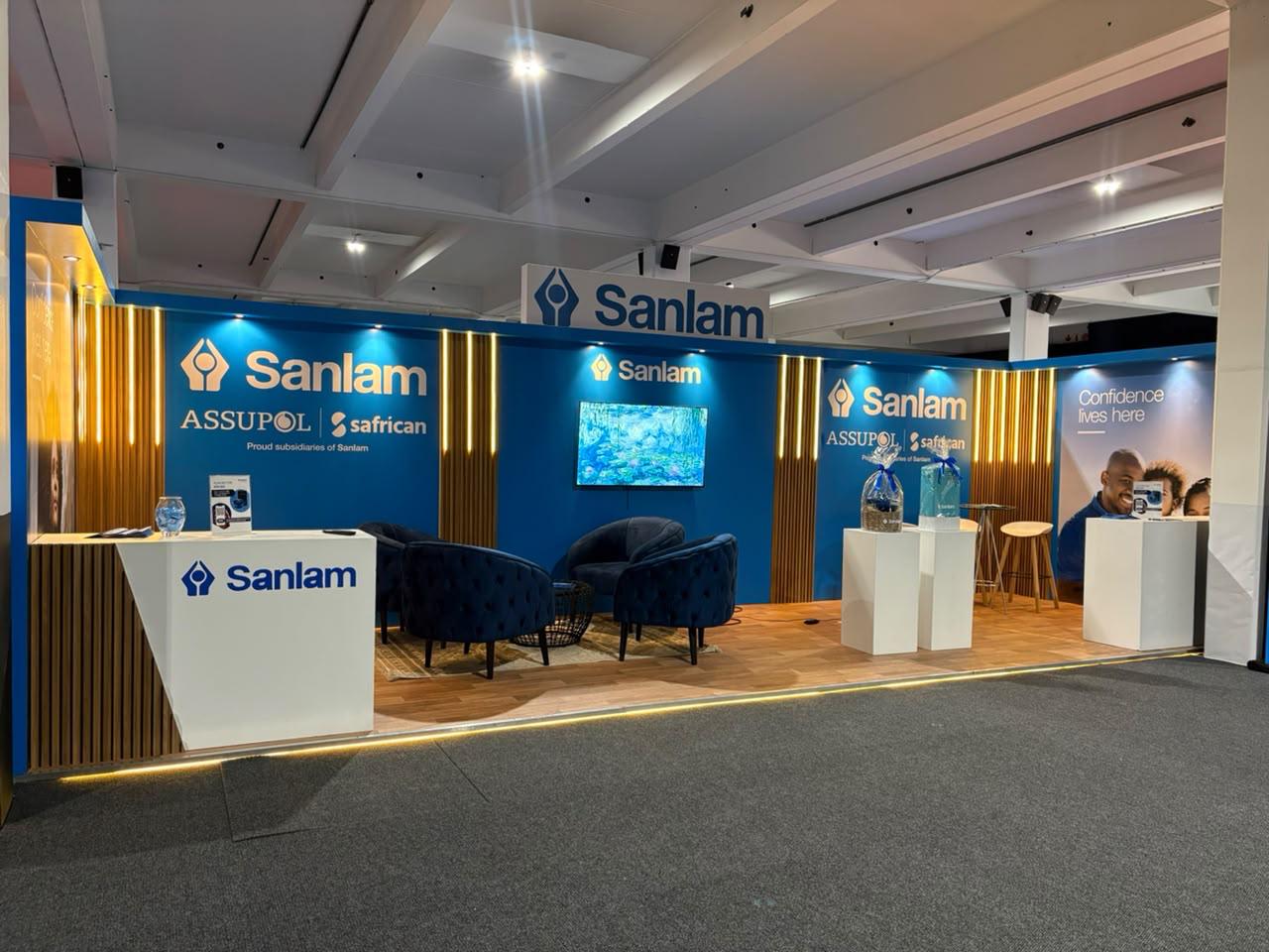 Custom exhibition stand built for Sanlam, with backlit wood-slat panelling, blue branded walling and 'Confidence lives here' messaging