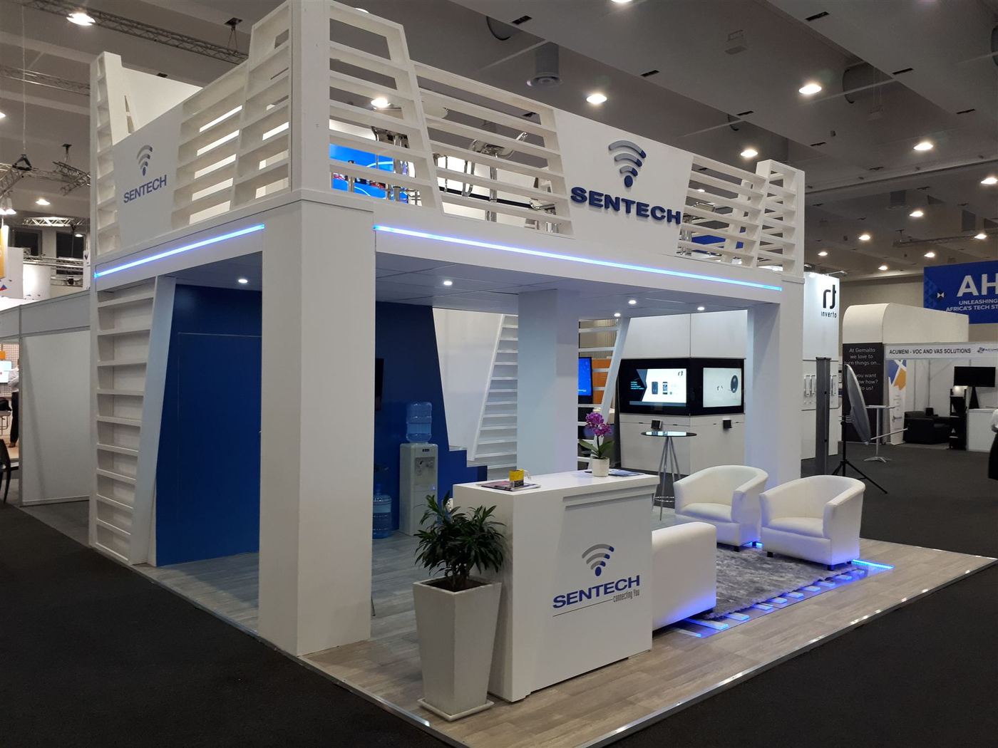Double-storey custom exhibition stand built for Sentech, with a mezzanine level and branded signage