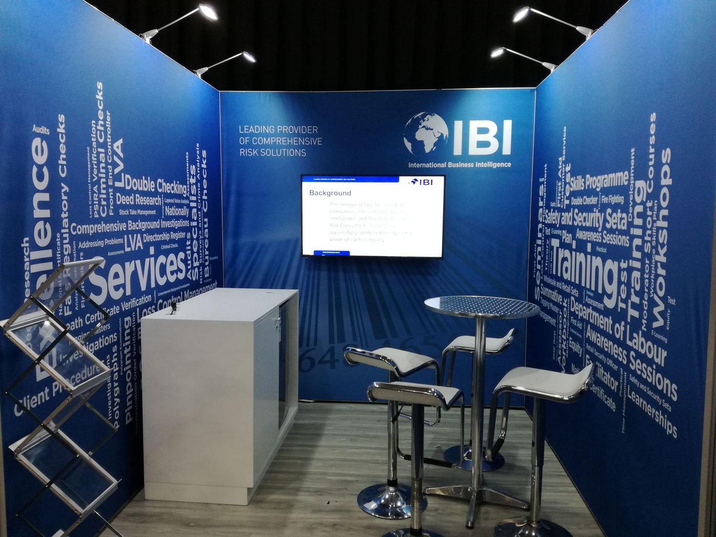 Shell scheme exhibition stand built for IBI (International Business Intelligence), with full-height word-cloud graphic panelling and high bar seating