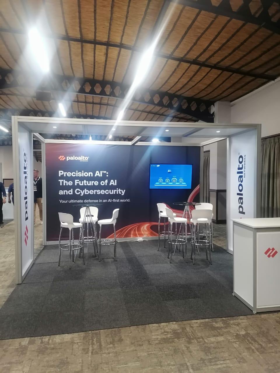 Shell scheme exhibition stand built for Palo Alto Networks, with a branded feature wall, screen and high bar seating